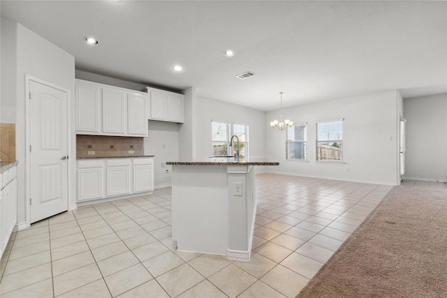 kitchen featuring light tile patterned floors, tasteful backsplash, visible vents, a chandelier, and a sink