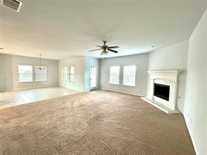 unfurnished living room with ceiling fan, a healthy amount of sunlight, and carpet floors