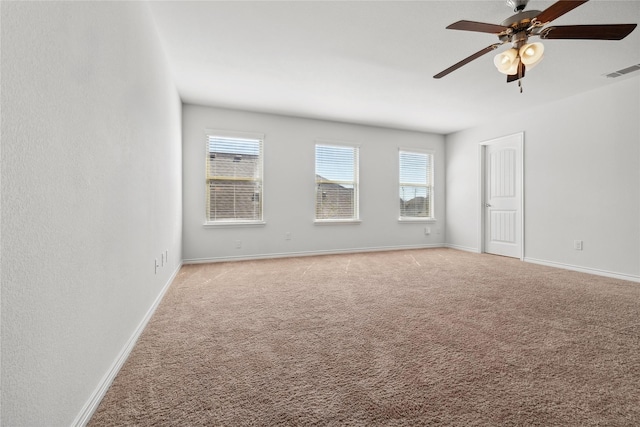 empty room with light carpet, ceiling fan, visible vents, and baseboards