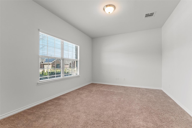 empty room with baseboards, visible vents, and carpet flooring