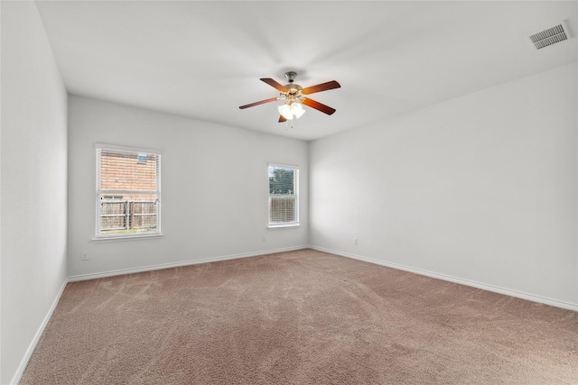 unfurnished room with ceiling fan, carpet floors, visible vents, and baseboards