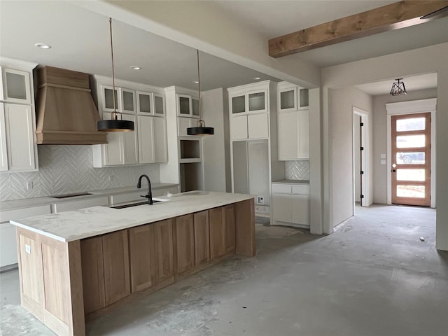 kitchen with sink, white cabinetry, decorative light fixtures, an island with sink, and custom range hood