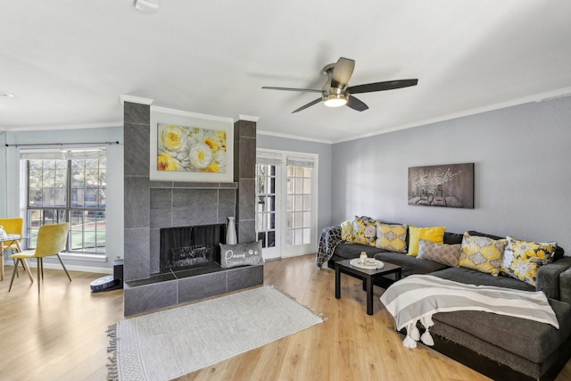 living room featuring crown molding, hardwood / wood-style flooring, ceiling fan, and a tiled fireplace