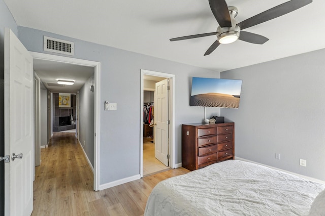 bedroom with a walk in closet, light hardwood / wood-style floors, a closet, and ceiling fan