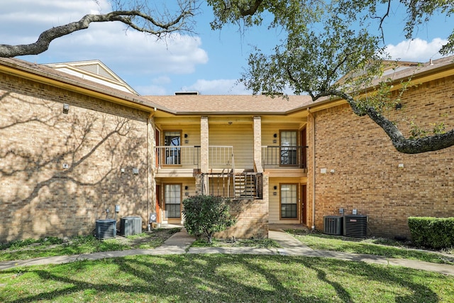 exterior space featuring a balcony, a yard, and central AC unit