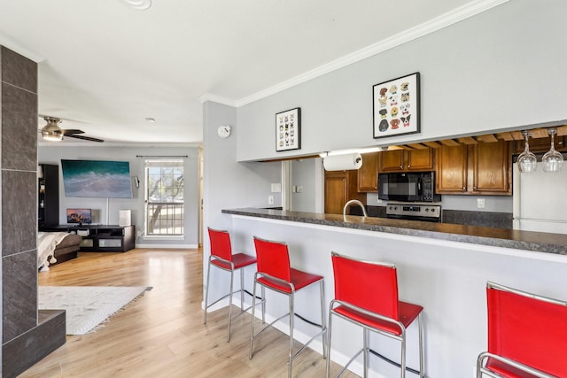 kitchen with stainless steel electric stove, a breakfast bar area, ornamental molding, ceiling fan, and light hardwood / wood-style floors