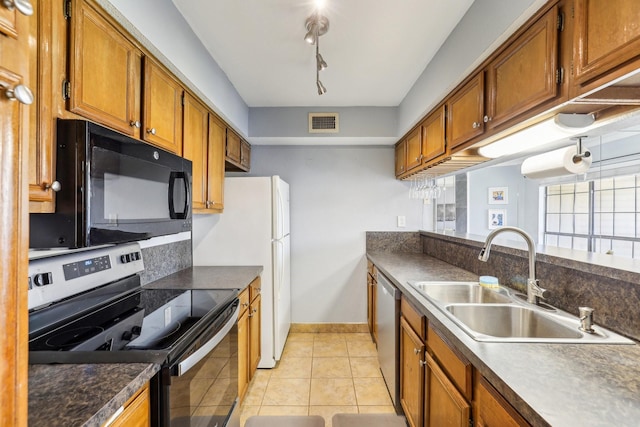 kitchen with appliances with stainless steel finishes, rail lighting, sink, and light tile patterned floors