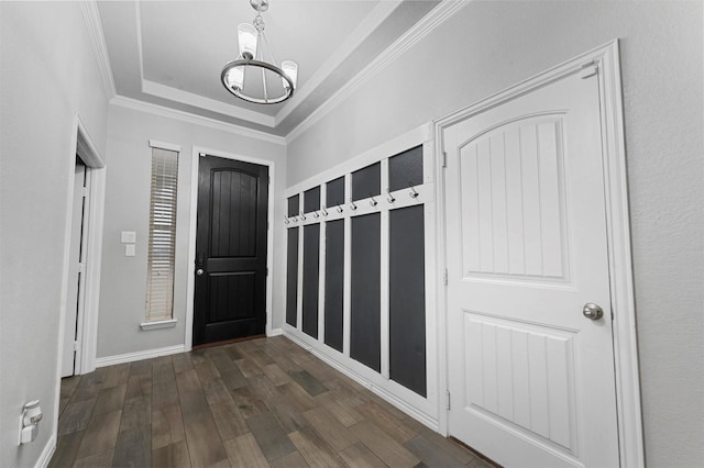 entrance foyer featuring dark hardwood / wood-style floors, ornamental molding, a raised ceiling, and a chandelier