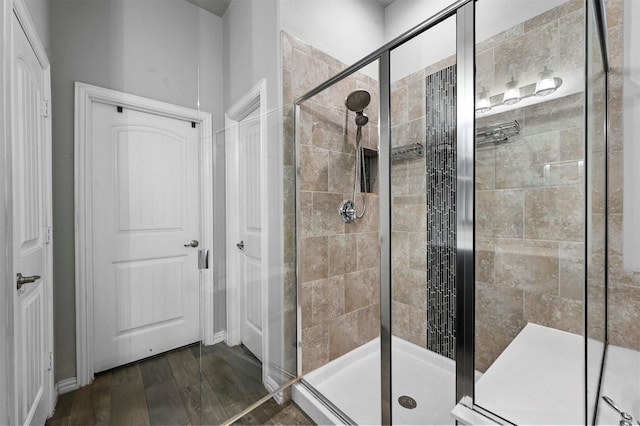 bathroom with hardwood / wood-style flooring and a shower with shower door