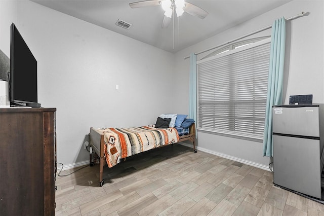 bedroom with stainless steel fridge, ceiling fan, and light hardwood / wood-style flooring