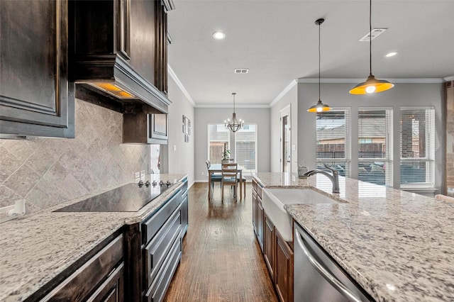 kitchen featuring sink, light stone countertops, hanging light fixtures, and black electric stovetop