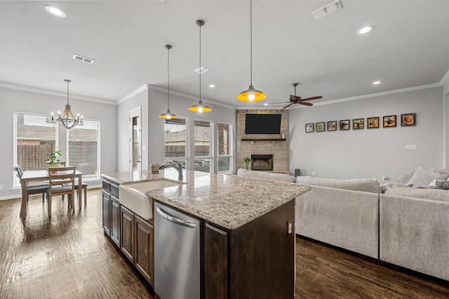 kitchen with pendant lighting, sink, a kitchen island with sink, dark brown cabinets, and a fireplace