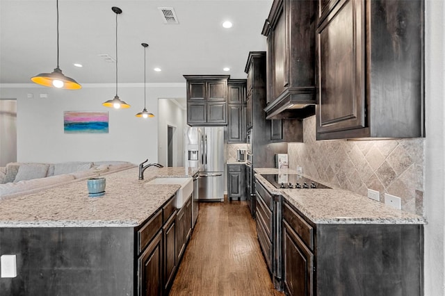 kitchen featuring sink, stainless steel fridge, an island with sink, pendant lighting, and stove