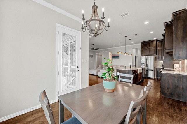 dining space featuring crown molding, dark hardwood / wood-style floors, ceiling fan with notable chandelier, and sink