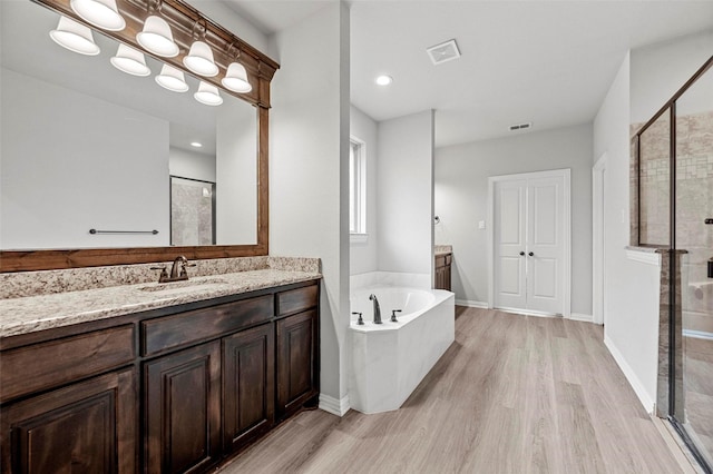 bathroom featuring vanity, separate shower and tub, and hardwood / wood-style floors