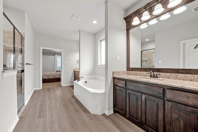 bathroom with vanity, hardwood / wood-style floors, and plus walk in shower