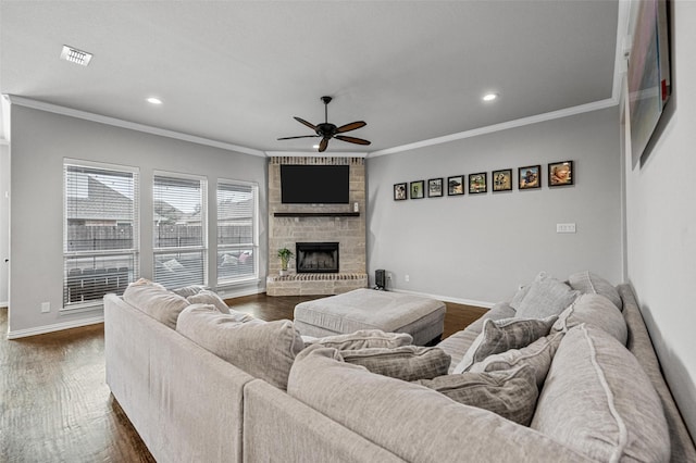 living room featuring ornamental molding, a stone fireplace, ceiling fan, and dark hardwood / wood-style flooring