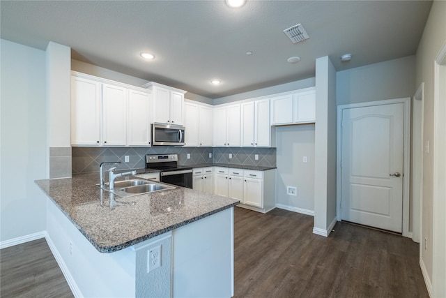 1267 Jones Trl, Lewisville, TX 75077 - kitchen featuring stainless steel appliances, a sink, a peninsula, dark wood-style floors, and dark stone counters