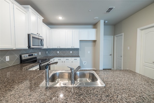 1267 Jones Trl, Lewisville, TX 75077 - kitchen featuring appliances with stainless steel finishes, a sink, white cabinetry, tasteful backsplash, and dark stone countertops