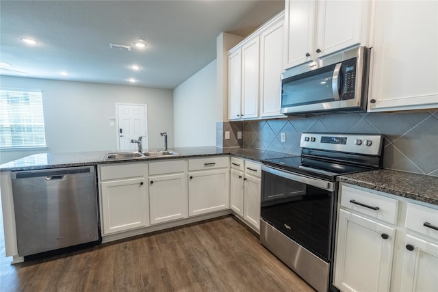 1267 Jones Trl, Lewisville, TX 75077 - kitchen with stainless steel appliances, a sink, a peninsula, dark wood finished floors, and white cabinets