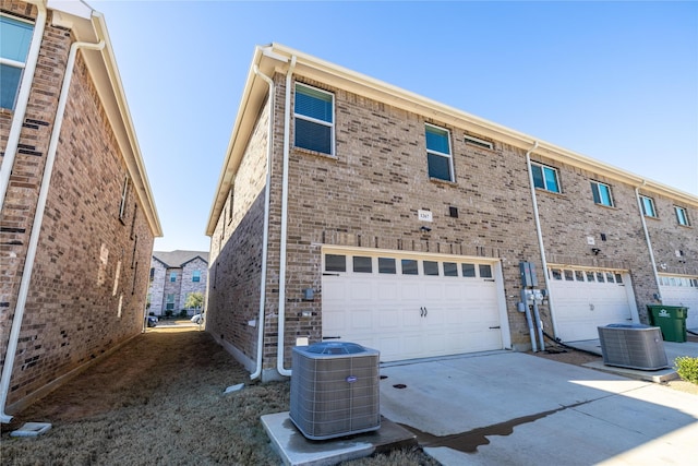 1267 Jones Trl, Lewisville, TX 75077 - rear view of house with central AC unit, an attached garage, driveway, and brick siding