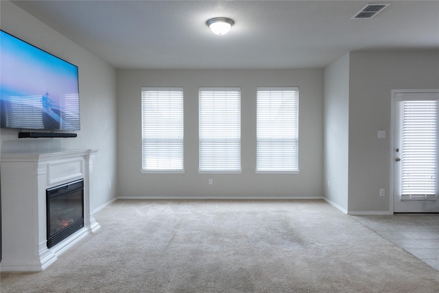 unfurnished living room with light carpet and a wealth of natural light