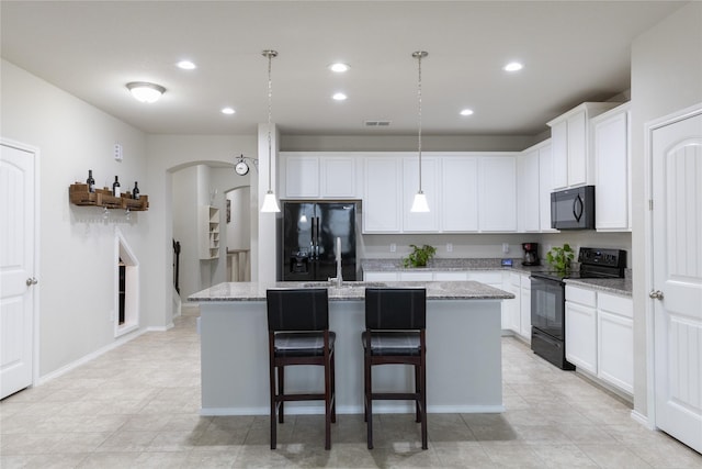 kitchen with a kitchen island with sink, hanging light fixtures, and black appliances