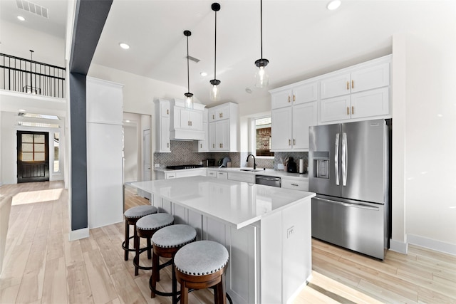 kitchen with stainless steel appliances, hanging light fixtures, a center island, and white cabinets