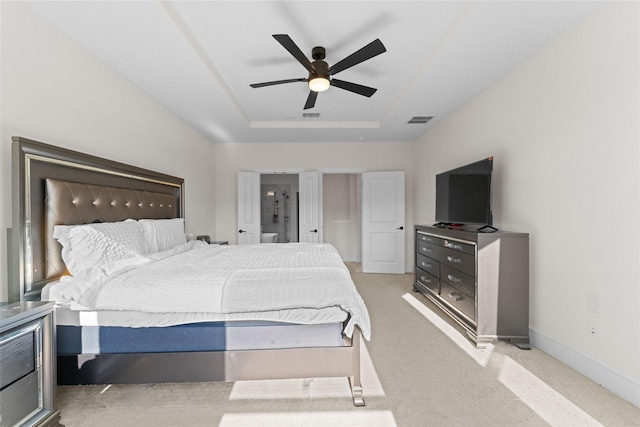 bedroom featuring a raised ceiling, light colored carpet, and ceiling fan