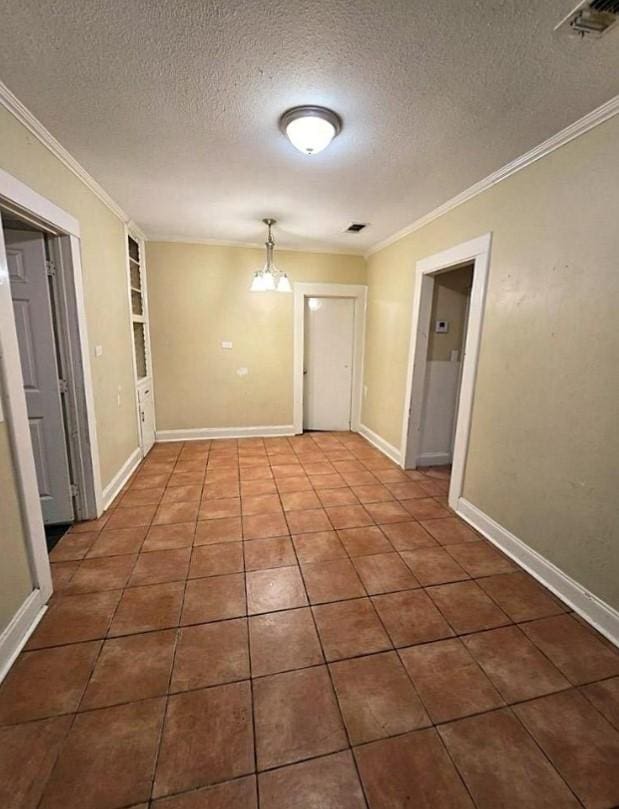 spare room featuring ornamental molding, dark tile patterned flooring, and a notable chandelier