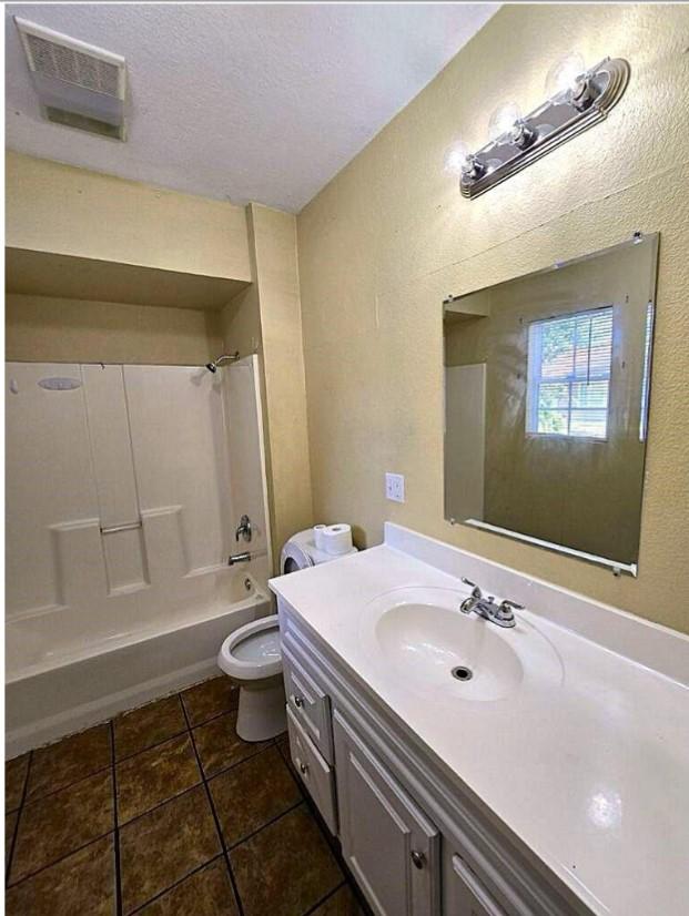 full bathroom featuring bathtub / shower combination, tile patterned flooring, vanity, toilet, and a textured ceiling