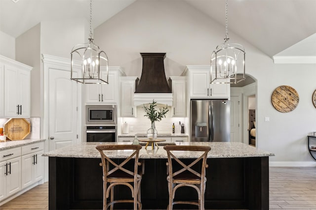 kitchen with appliances with stainless steel finishes, an island with sink, and an inviting chandelier