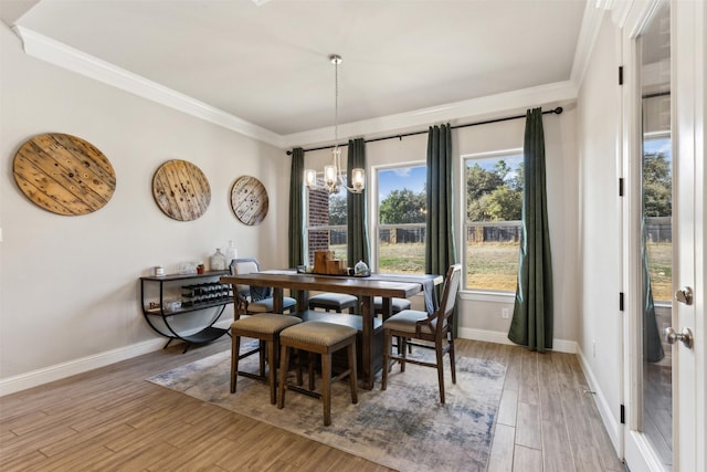 dining area with light wood-type flooring, crown molding, baseboards, and an inviting chandelier