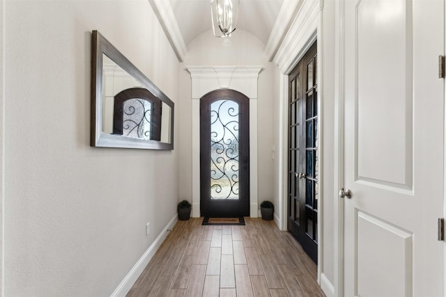 entrance foyer with light wood-type flooring, vaulted ceiling, baseboards, and an inviting chandelier