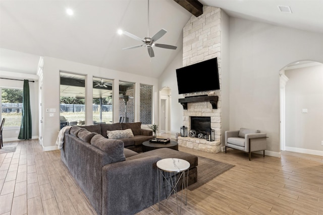 living room featuring high vaulted ceiling, beam ceiling, a fireplace, and light wood-style flooring