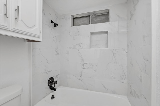 bathroom featuring tiled shower / bath combo and toilet