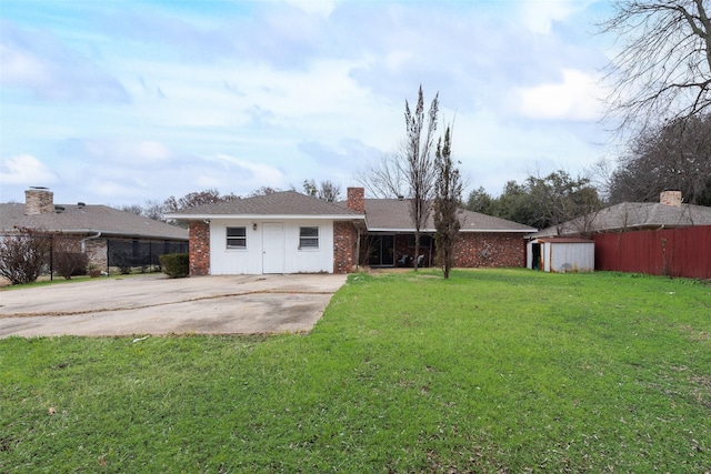 rear view of property featuring a storage unit and a lawn