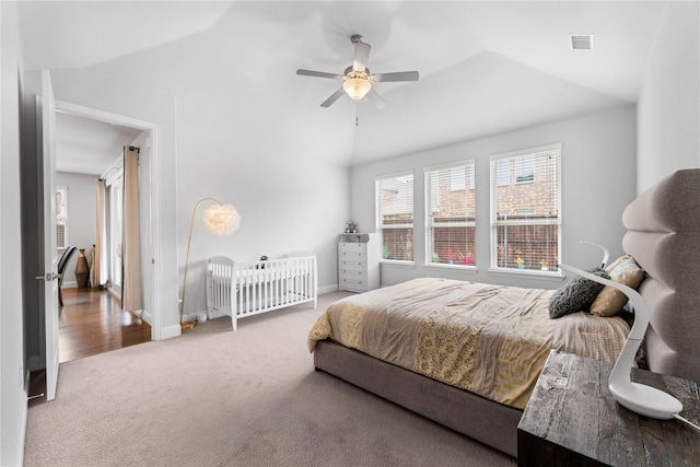 carpeted bedroom with a ceiling fan, lofted ceiling, visible vents, and baseboards