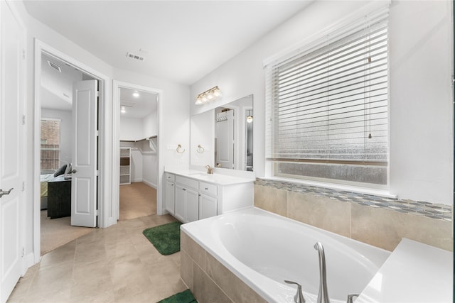 bathroom with visible vents, a garden tub, tile patterned flooring, a walk in closet, and vanity