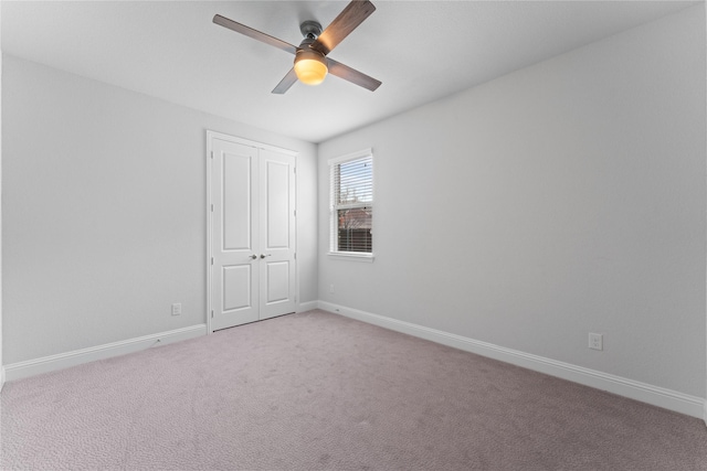 spare room featuring baseboards, ceiling fan, and light colored carpet