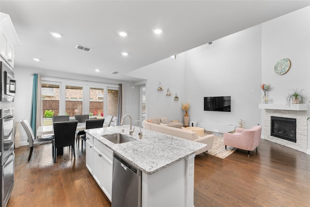 kitchen featuring an island with sink, white cabinetry, appliances with stainless steel finishes, and open floor plan