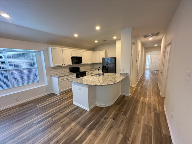 kitchen with sink, backsplash, light stone counters, black appliances, and white cabinets