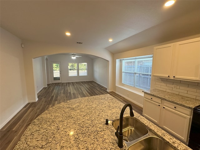 kitchen featuring light stone counters, sink, vaulted ceiling, and white cabinets