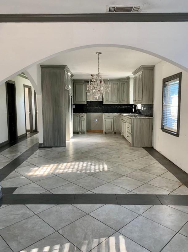 kitchen with sink, hanging light fixtures, backsplash, a notable chandelier, and light tile patterned flooring