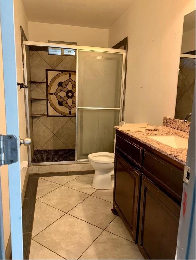 bathroom with vanity, an enclosed shower, tile patterned flooring, and toilet