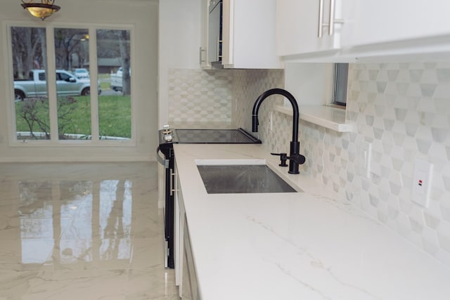 kitchen with white cabinetry, sink, tasteful backsplash, and light stone countertops