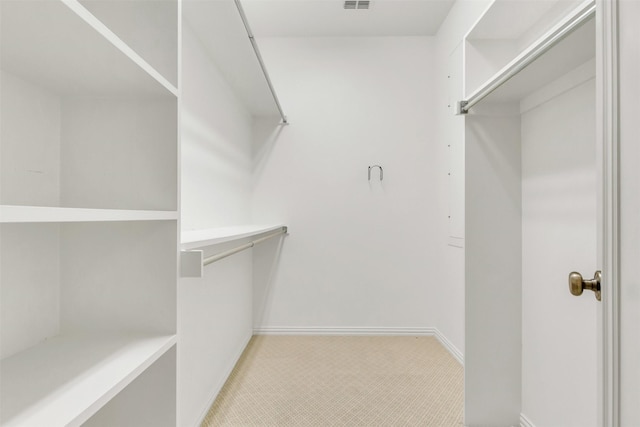 walk in closet featuring light colored carpet