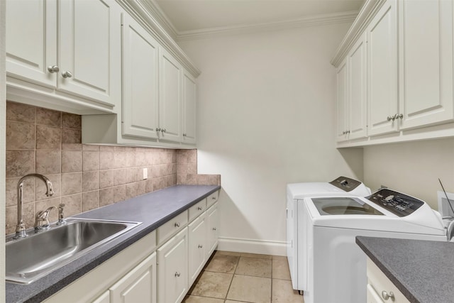 laundry area with washing machine and clothes dryer, sink, crown molding, cabinets, and light tile patterned floors