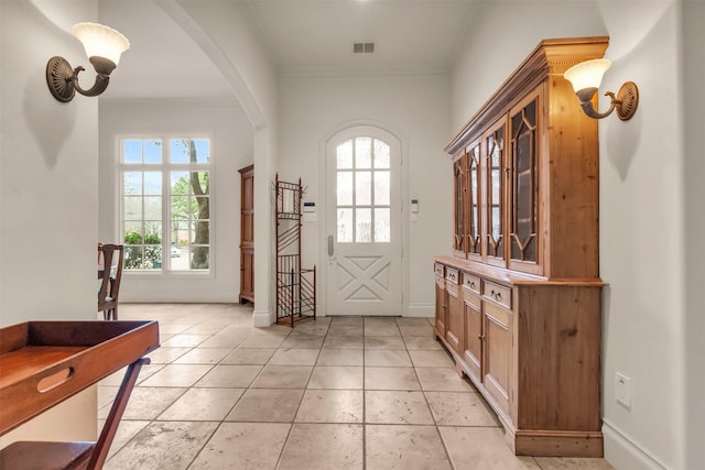 doorway to outside with ornamental molding and light tile patterned flooring