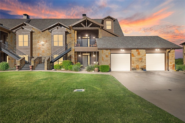 view of front of property featuring a garage, a balcony, and a yard